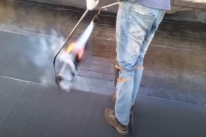 Kitchener Roofing employee installing flat roof with high heat fire.