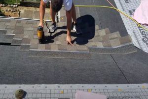 JP Kitchener Roofing employee installing shingles on a roof.