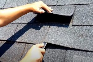 Worker for Kitchener Roofing checking that all shingles on residential roof are good.