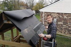 Kitchener Roofing worker adding shingles to a small roof.