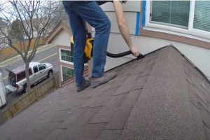 JP Kitchener Roofing worker cleaning the roof to repair it